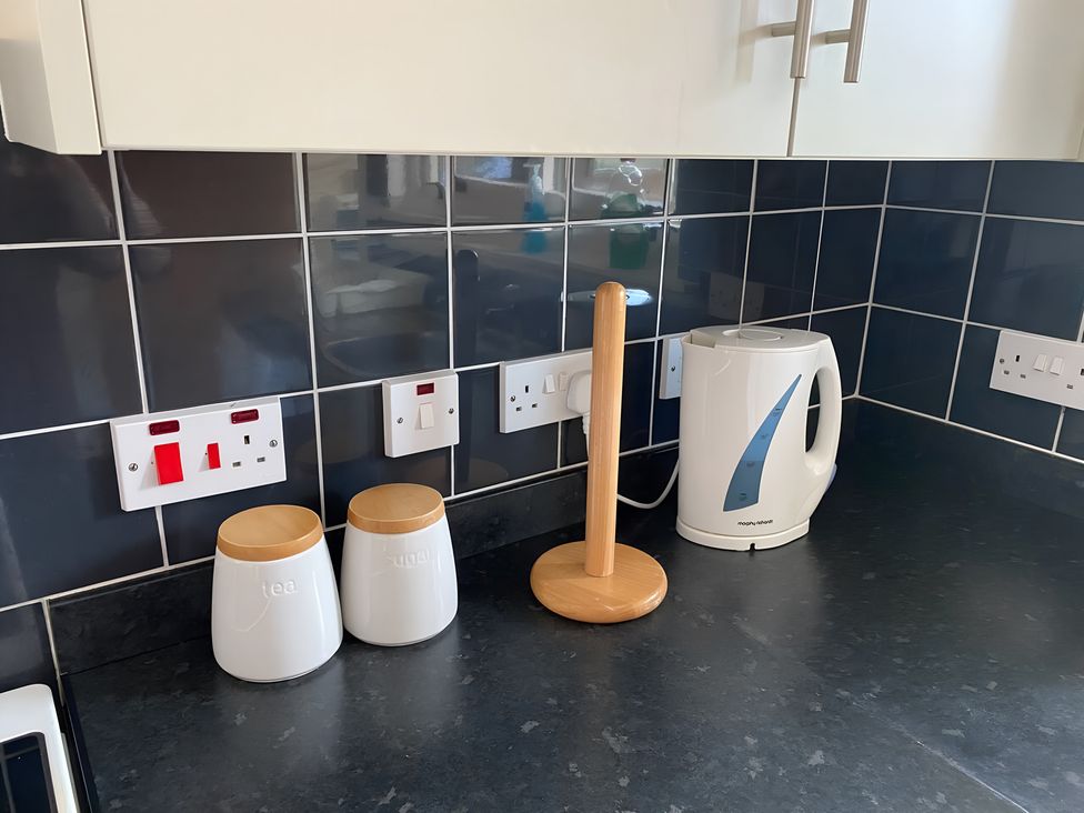 A kitchen countertop with a kettle and containers for tea and sugar at 9 Creag An Iolaire Near Portree