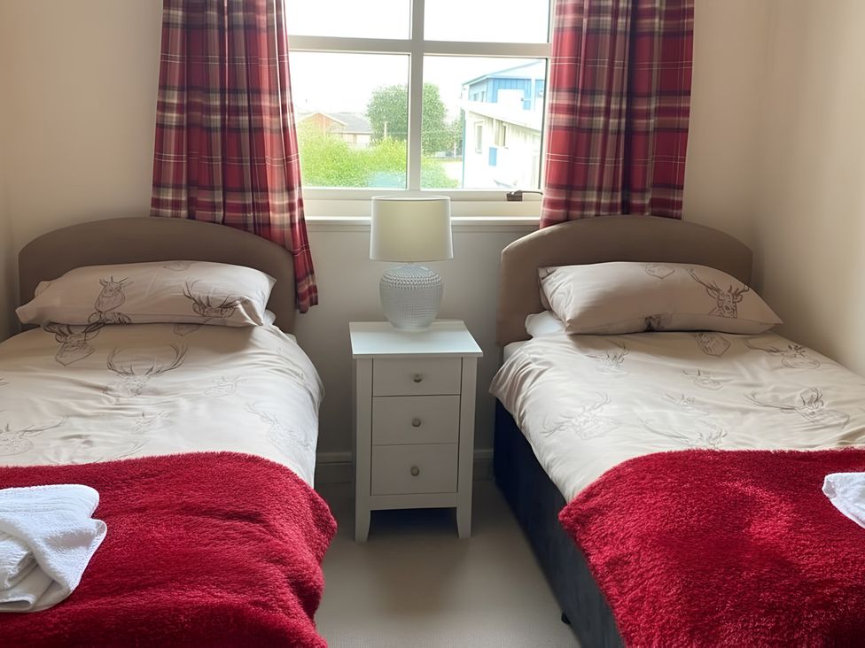 A bedroom with two beds and a bedside table at 9 Creag An Iolaire near Portree