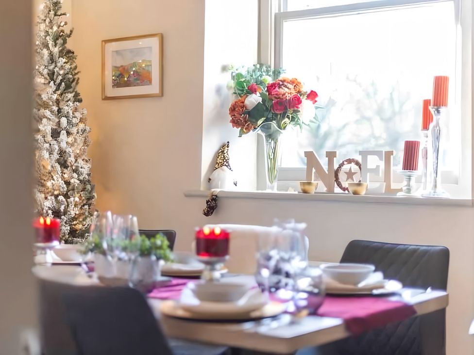 A dining room with a table set for dinner and a decorated Christmas tree at 29 Chapel Street Appleby-In-Westmorland