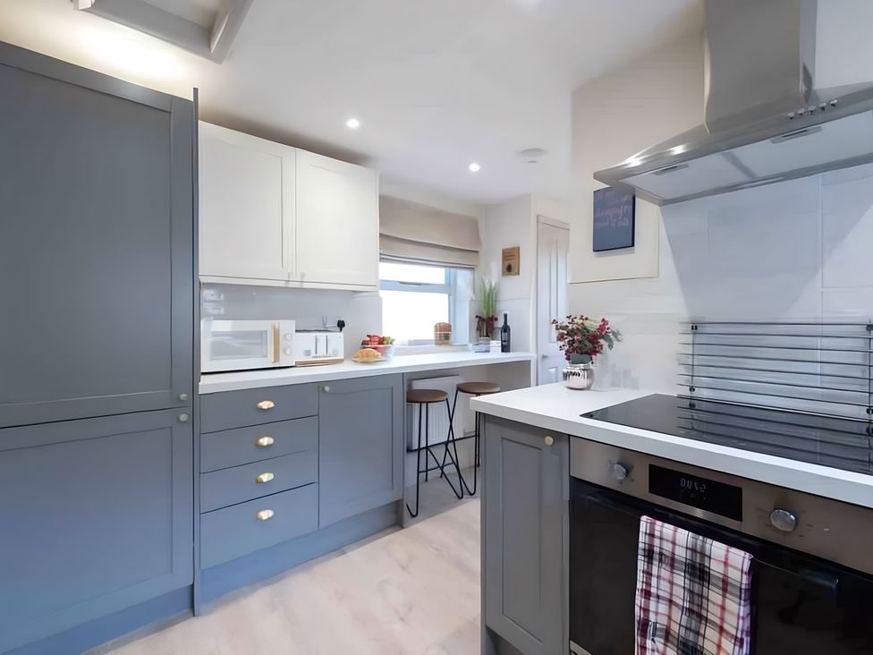A kitchen with bar stools and a microwave at 29 Chapel Street in Appleby-In-Westmorland