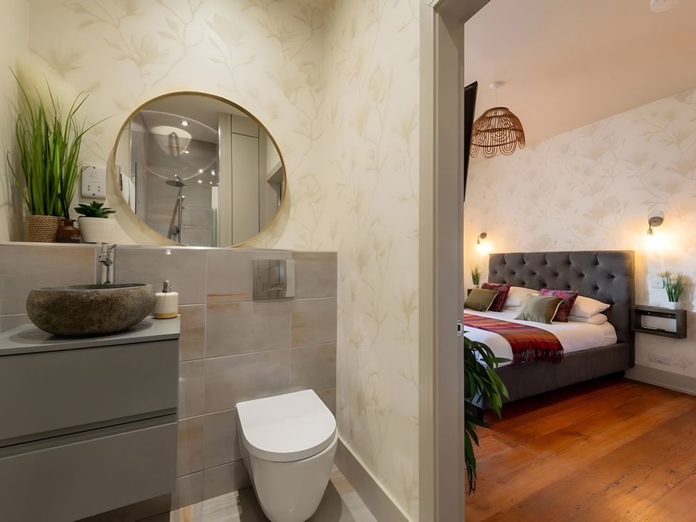 A bathroom with a toilet and sink looking into a bedroom at 29 Chapel Street in Appleby-In-Westmorland