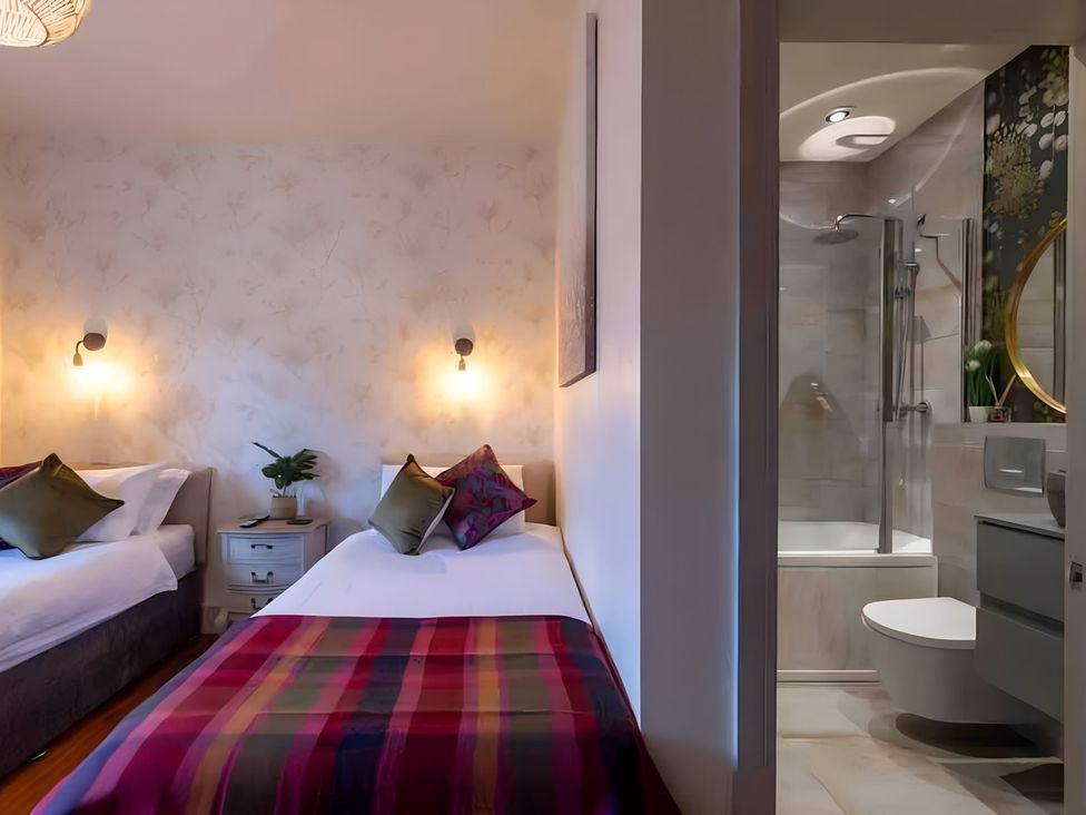 A bedroom with two beds and an adjoining bathroom at 29 Chapel Street Appleby-In-Westmorland