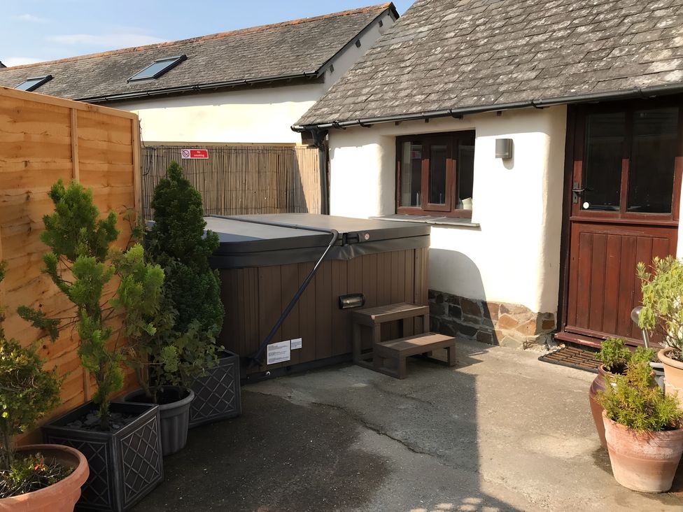 An outdoor area featuring a hot tub and potted plants at Granary Barn in Winkleigh
