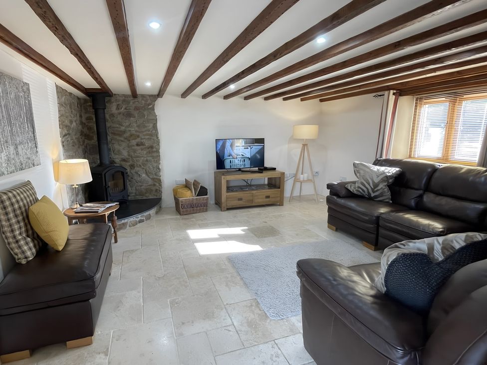 A living room with a sofa, television, and wood stove at Granary Barn in Winkleigh