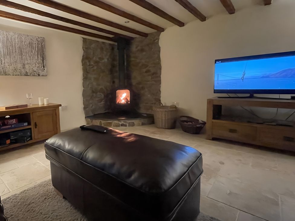 A living room with a fireplace and television at Granary Barn in Winkleigh