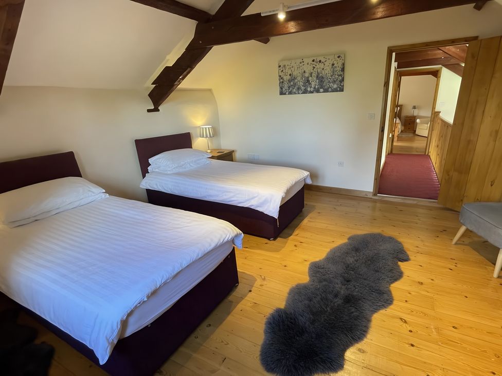 A bedroom with two beds and a nightstand at Granary Barn in Winkleigh