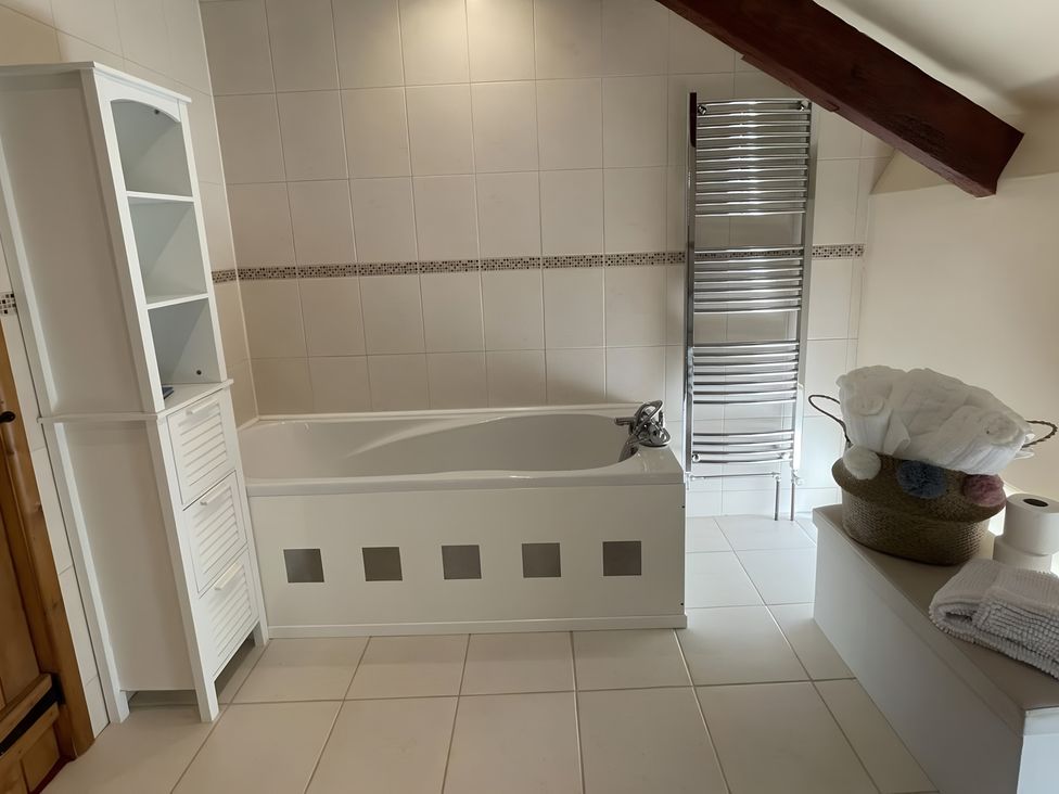 A bathroom with a bathtub and towel warmer at Granary Barn in Winkleigh
