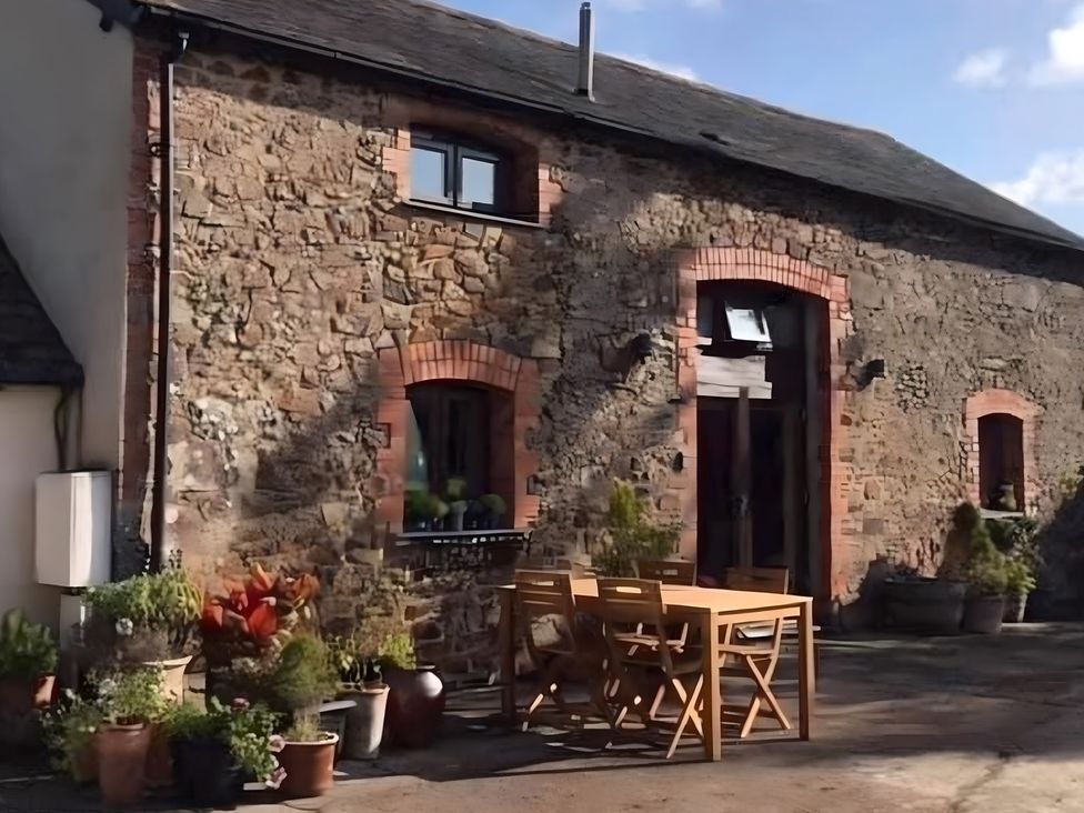 An outdoor area with a wooden table and plants at Granary Barn in Winkleigh