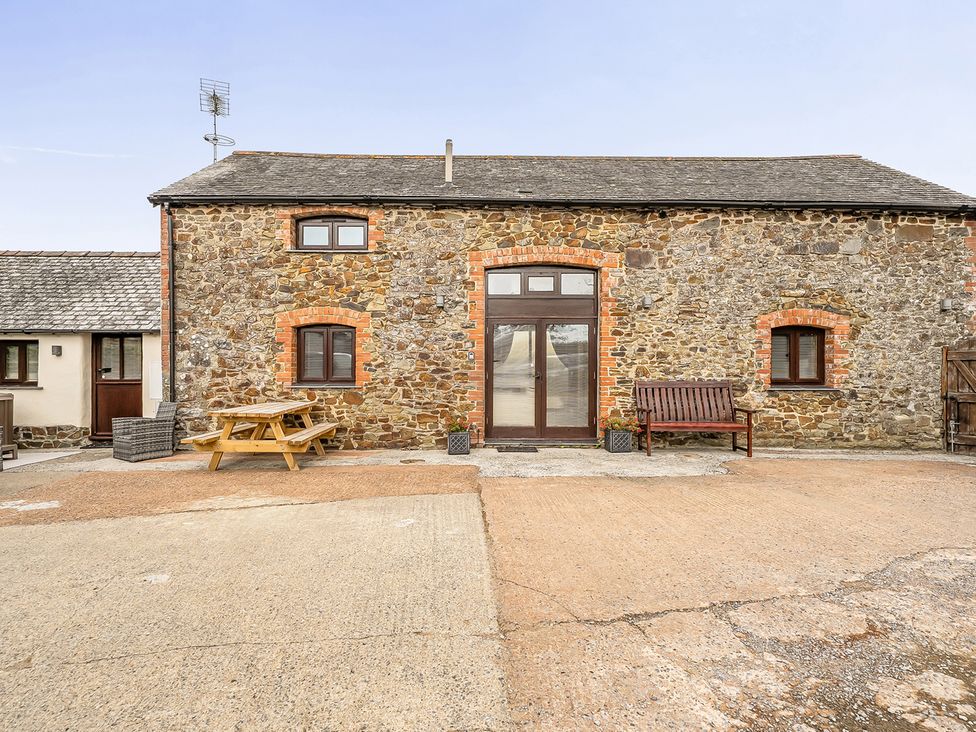 An outdoor area with a stone building and seating arrangements at Granary Barn Winkleigh