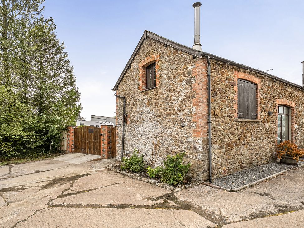 An outdoor view of a stone building with a wooden gate at Granary Barn Winkleigh