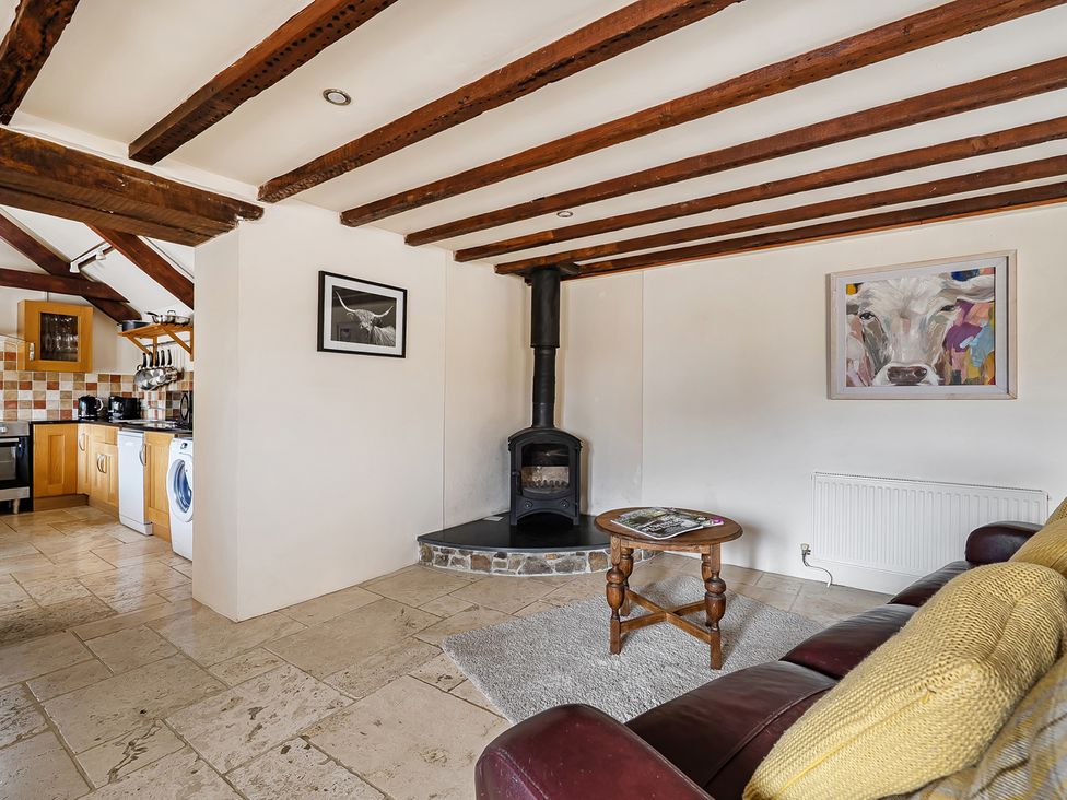 A living room with a wood burner and kitchen units at Granary Barn Winkleigh