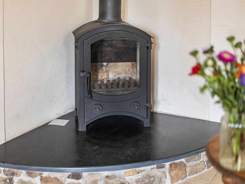 A wood stove with a stone base in the living room at Granary Barn Winkleigh