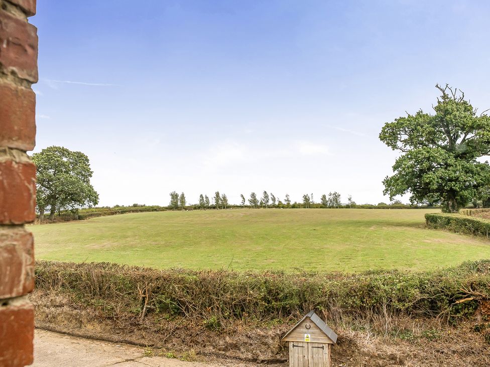 A view of a field with trees and a dog house at Granary Barn in Winkleigh