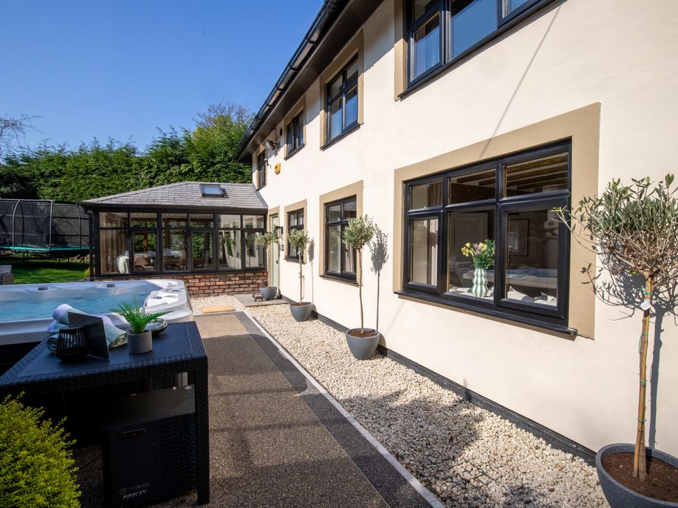 An outdoor area with a hot tub and plants at Rainbow Cottage Aughton near Ormskirk