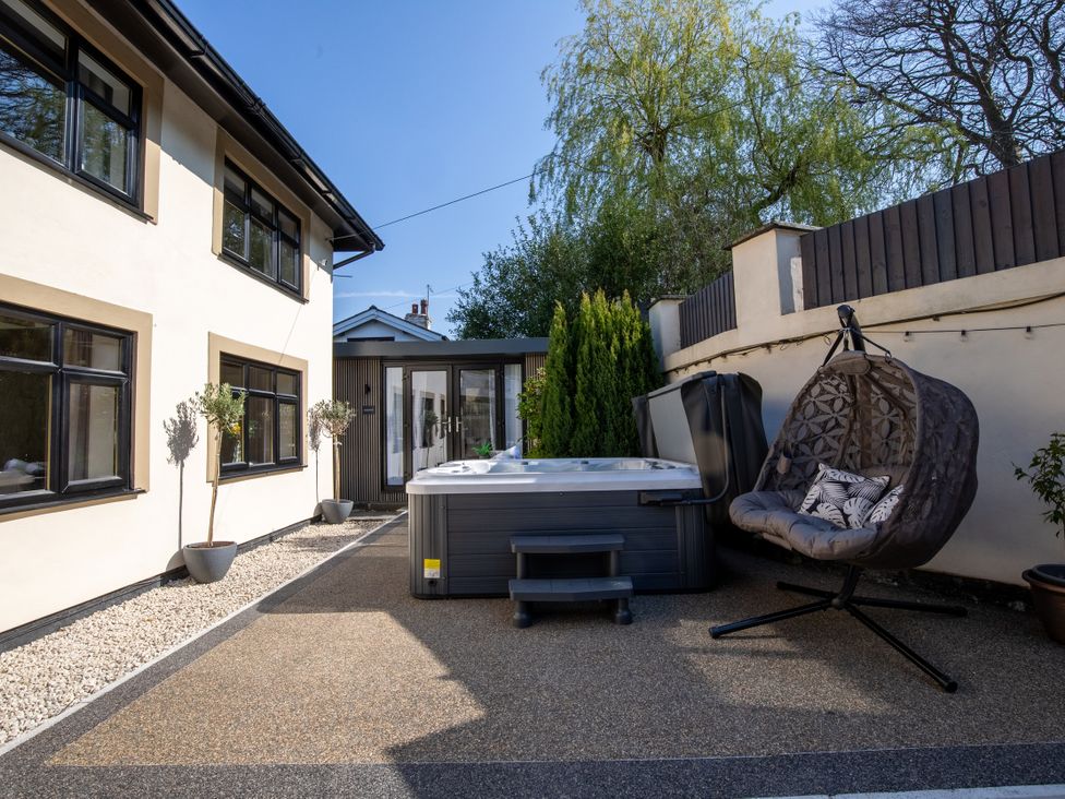 An outdoor area with a hot tub and a hanging chair at Rainbow Cottage Aughton near Ormskirk