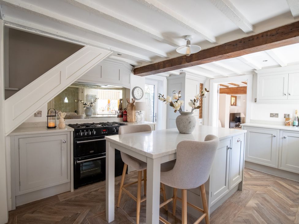 A kitchen with a stove and dining table at Rainbow Cottage in Aughton near Ormskirk