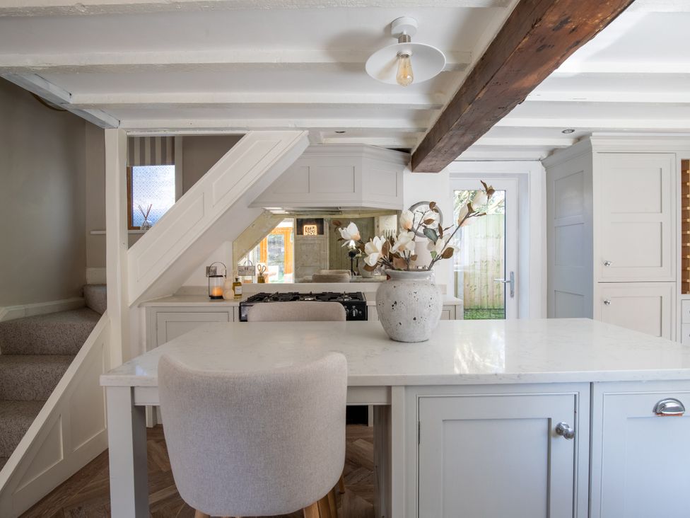 A kitchen with a staircase and a kitchen island at Rainbow Cottage Aughton near Ormskirk