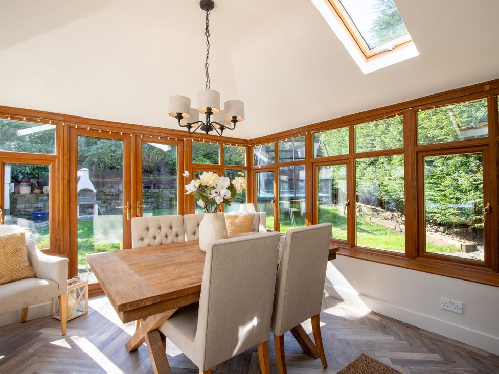 A conservatory with a dining table and chairs at Rainbow Cottage in Aughton near Ormskirk