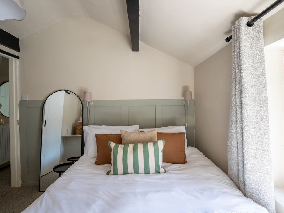 A bedroom with a bed and mirror at Rainbow Cottage in Aughton near Ormskirk