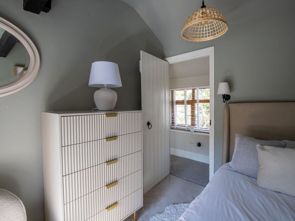 A bedroom with a dresser and a lamp at Rainbow Cottage in Aughton near Ormskirk