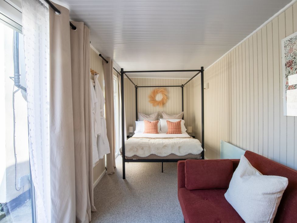 A bedroom with a canopy bed and a sofa at Rainbow Cottage in Aughton near Ormskirk