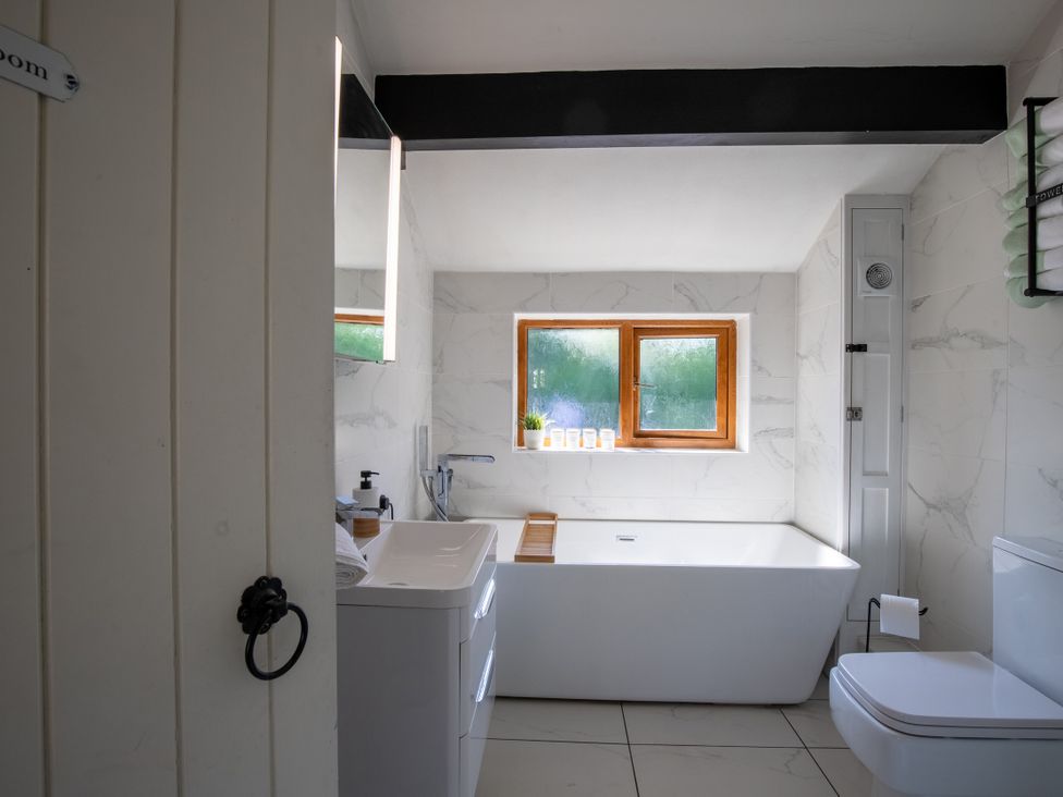 A bathroom with a bathtub, sink, toilet and a window at Rainbow Cottage Aughton near Ormskirk