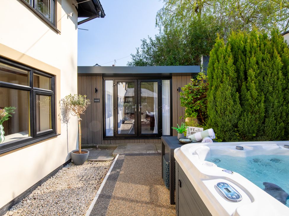 An outdoor area with a hot tub and garden features at Rainbow Cottage Aughton near Ormskirk