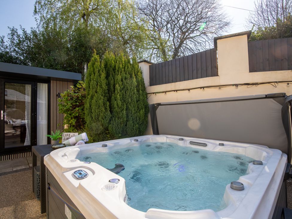 A hot tub with surrounding plants and a door at Rainbow Cottage Aughton near Ormskirk