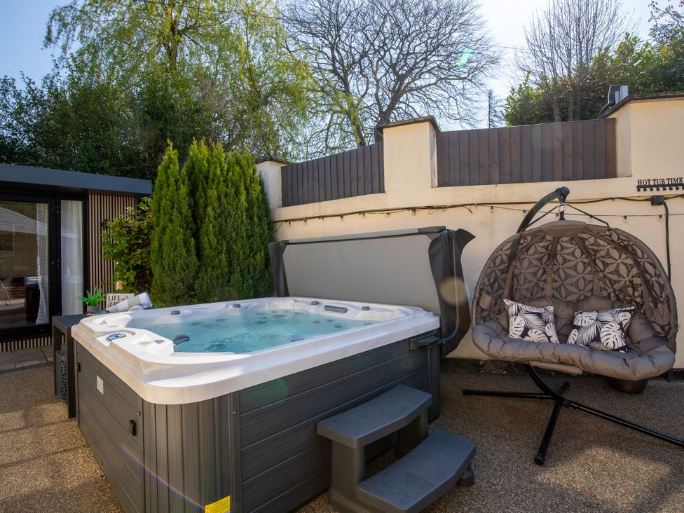 An outdoor area with a hot tub and a hanging chair at Rainbow Cottage in Aughton near Ormskirk
