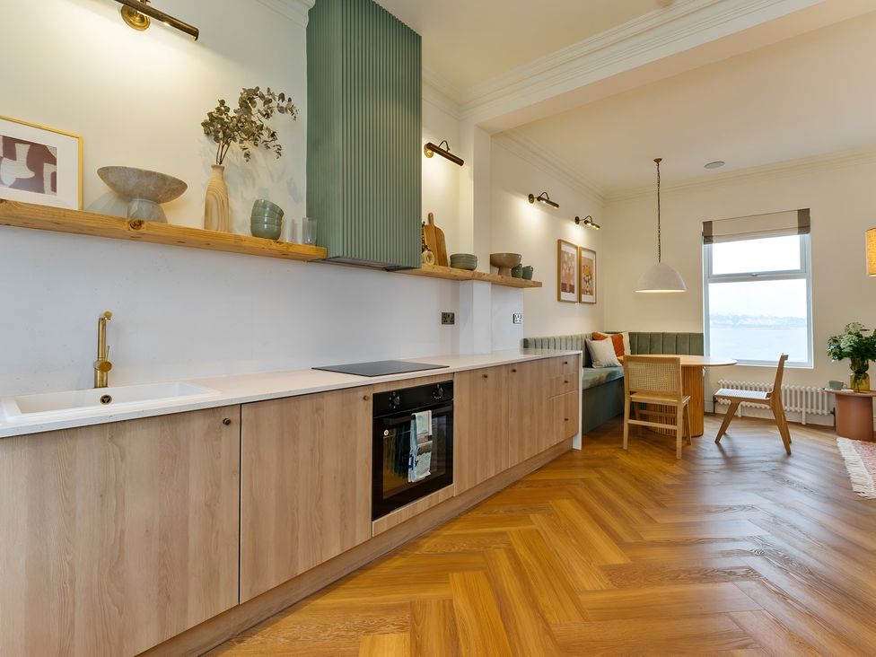 A kitchen with cabinets and a dining area at Seafront Apartment in Donaghadee