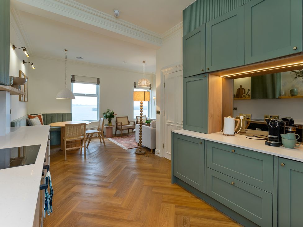 A kitchen with cabinets and a dining area at Seafront Apartment in Donaghadee
