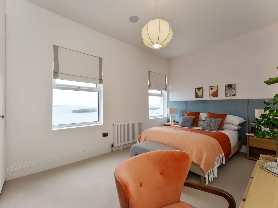 A bedroom with a bed, bedside table, and window at Seafront Apartment in Donaghadee