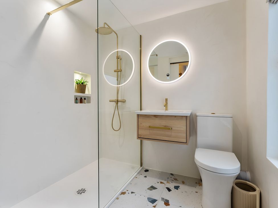 A bathroom with a shower, toilet, and vanity at Seafront Apartment in Donaghadee