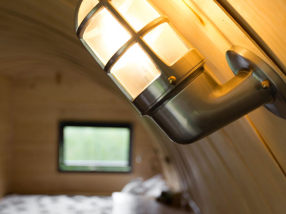 A wall lamp and window with a bed at Glamping pod-Luxury Glamping Retreat in Battle