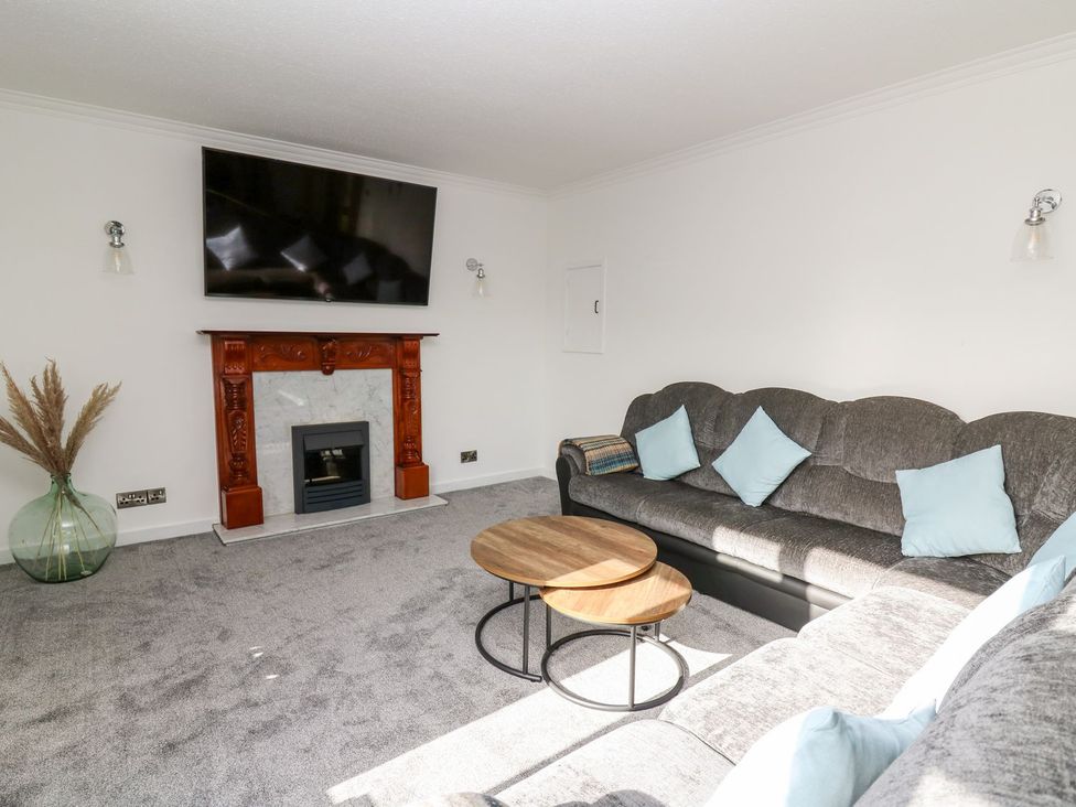 A living room with a sofa, coffee table, and fireplace at Tymelyn in Aberystwyth