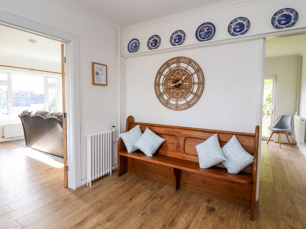 A hallway with a wooden bench and wall clock at Tymelyn, Aberystwyth