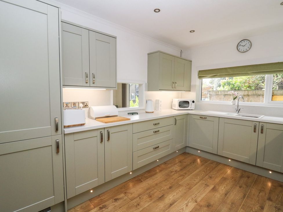 A kitchen with cabinets, sink, and appliances at Tymelyn Aberystwyth