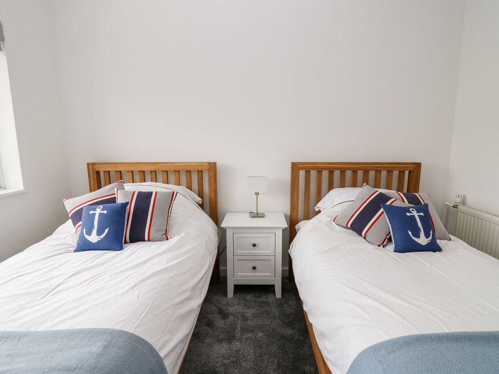 A bedroom with twin beds and a bedside table at Tymelyn in Aberystwyth