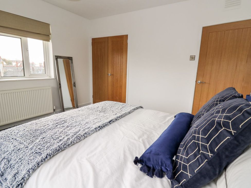 A bedroom with a bed and mirror at Tymelyn in Aberystwyth