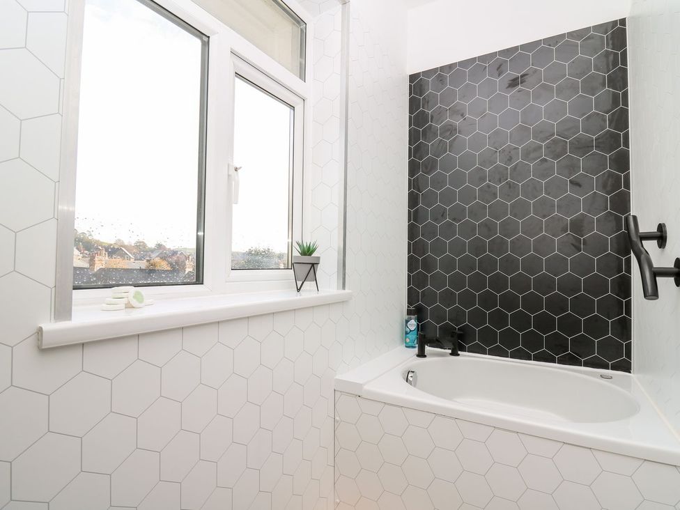 A bathroom with a bathtub and window at Tymelyn in Aberystwyth