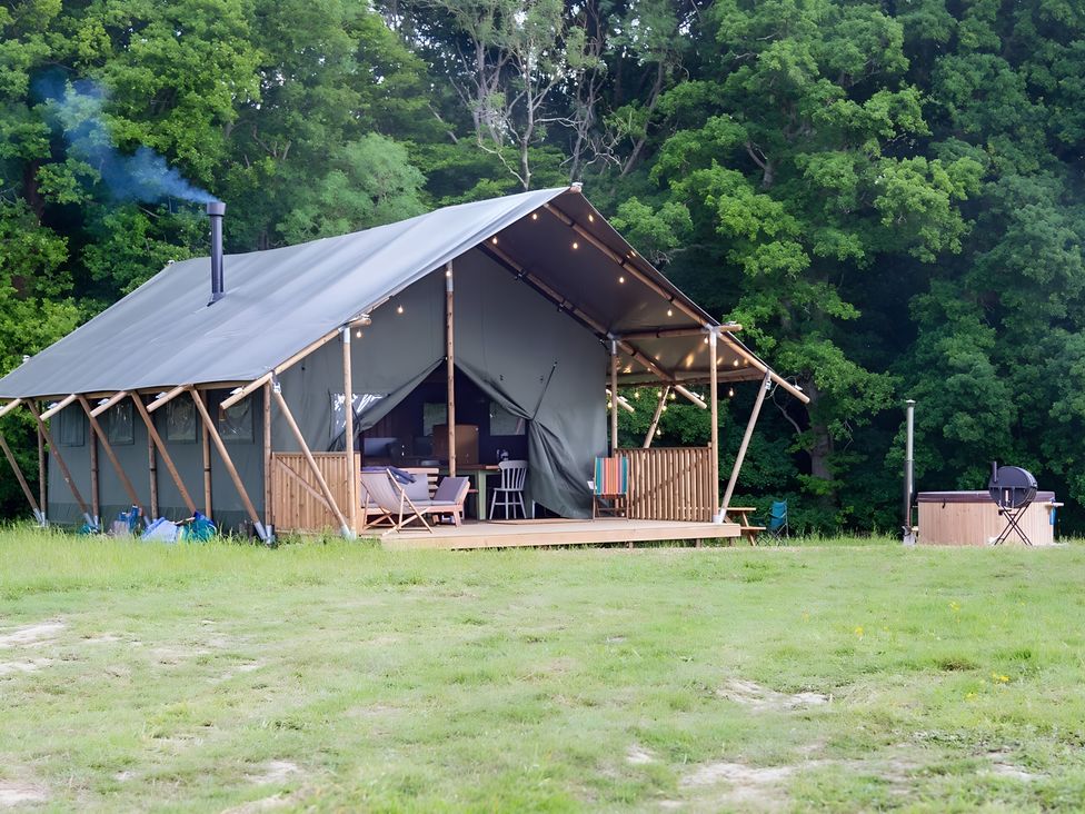 A tent with a wooden deck and seating area at Badger - Luxury Glamping Retreat in Battle