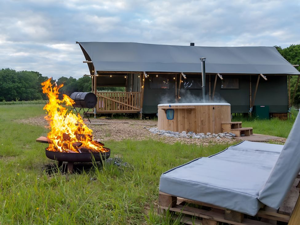 A fire pit and hot tub in front of a tent at Badger - Luxury Glamping Retreat in Battle
