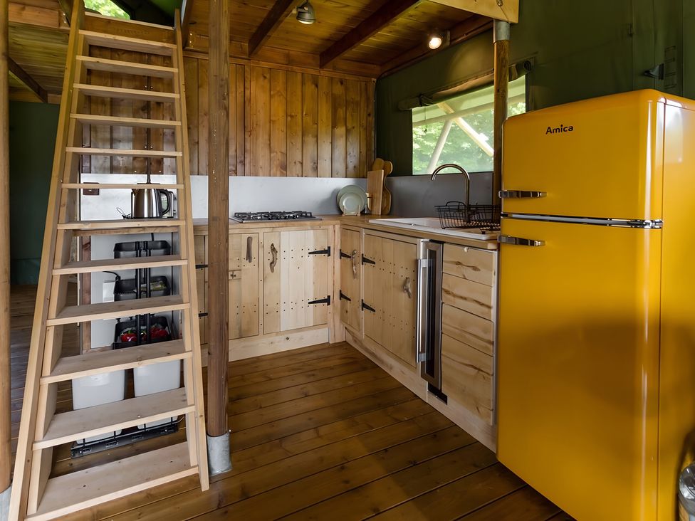 A kitchen with wooden cabinets and a yellow refrigerator at Badger - Luxury Glamping Retreat in Battle