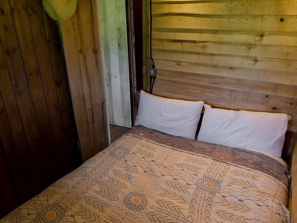 A bedroom with a bed and wooden walls at Badger - Luxury Glamping Retreat in Battle