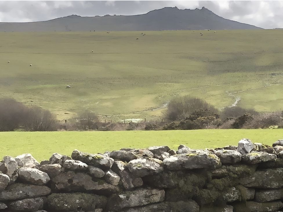 A view of a mountain and grassy field with a stone wall at Tylands in Camelford