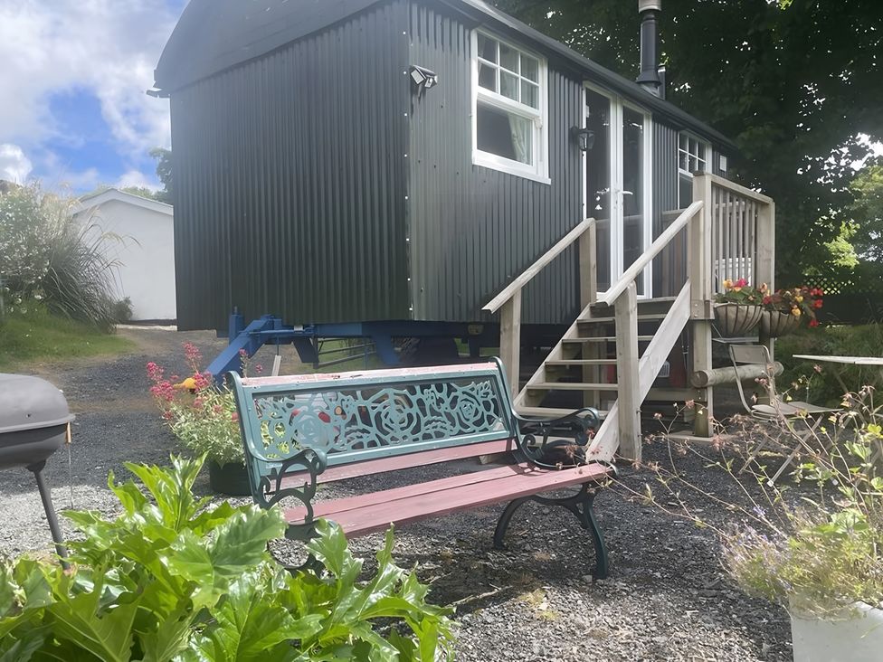 A shepherd's hut with steps and a bench at Tylands in Camelford