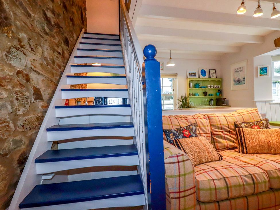 A living room with a staircase and sofa at Cubbs Corner Goonbell near St Agnes