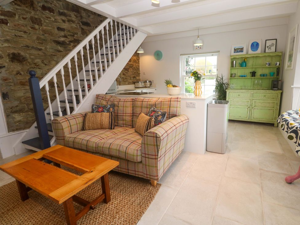 A living room with a sofa and kitchen counter at Cubs Corner in St Agnes