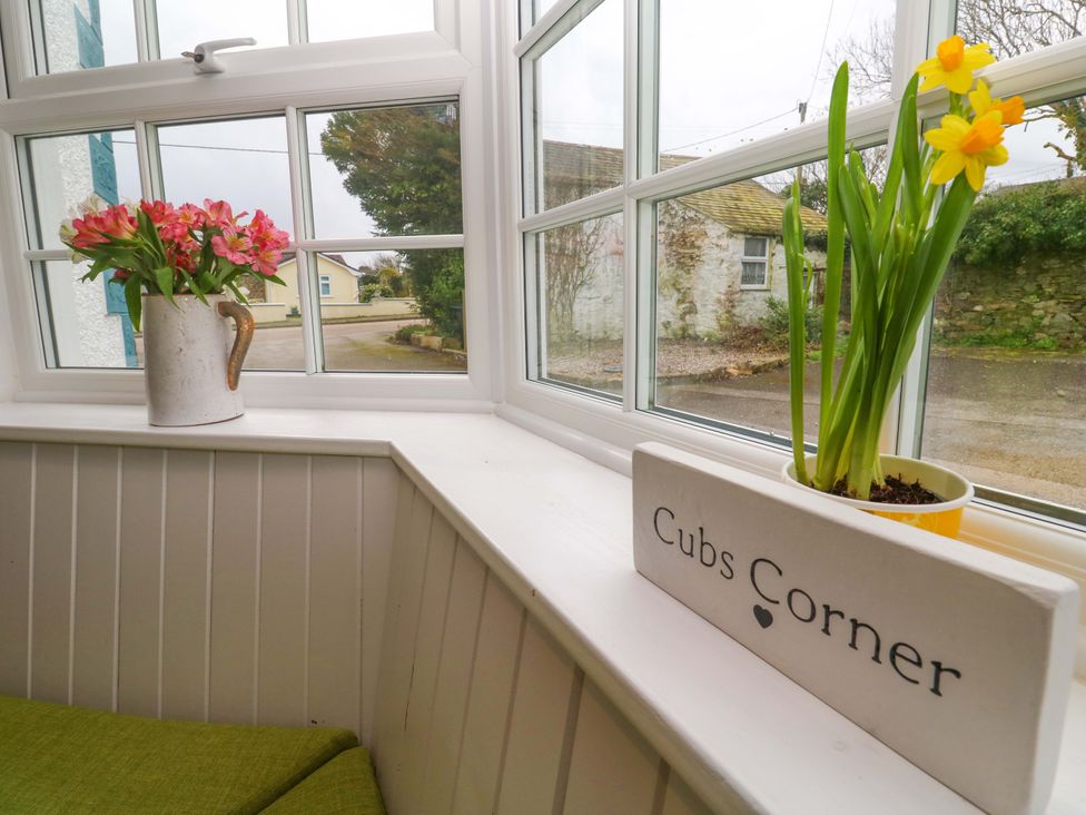 A sunroom with flowers and a sign at Cubs Corner in St Agnes