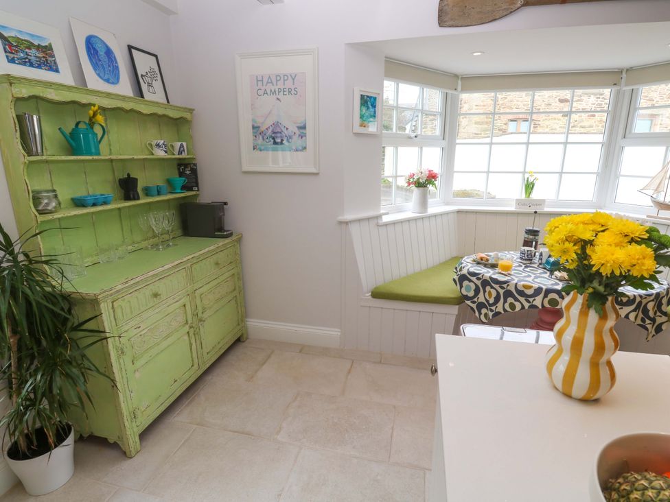 A dining room with a green cabinet and a table at Cubs Corner in St Agnes